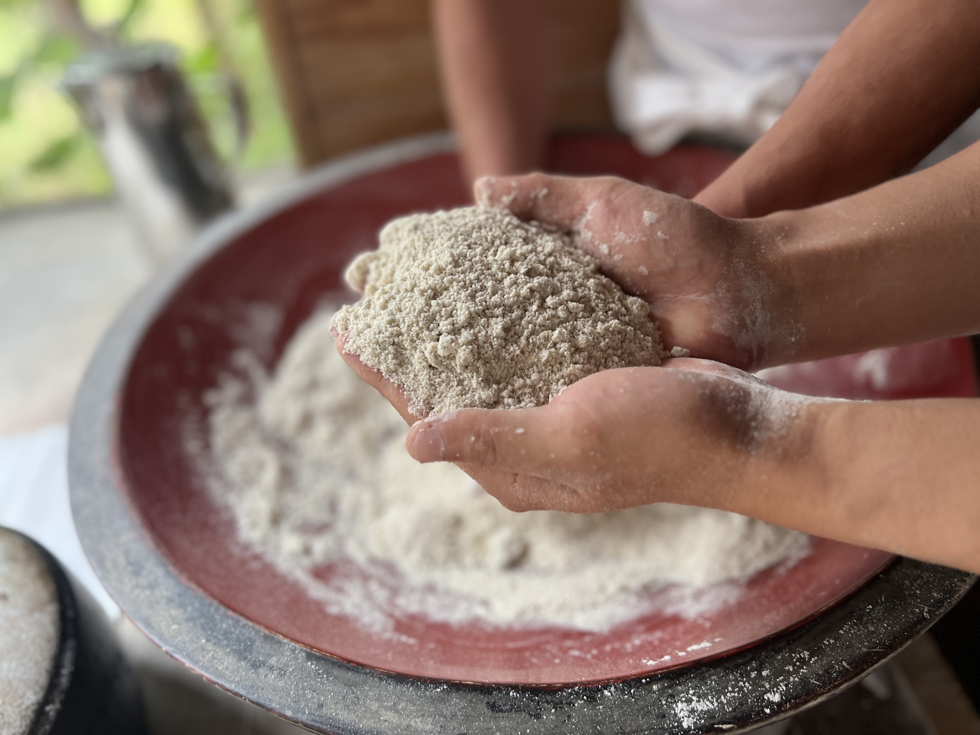 蕎麦打ちの手元。こねた蕎麦粉を打ち板の上で丁寧に広げる職人の手