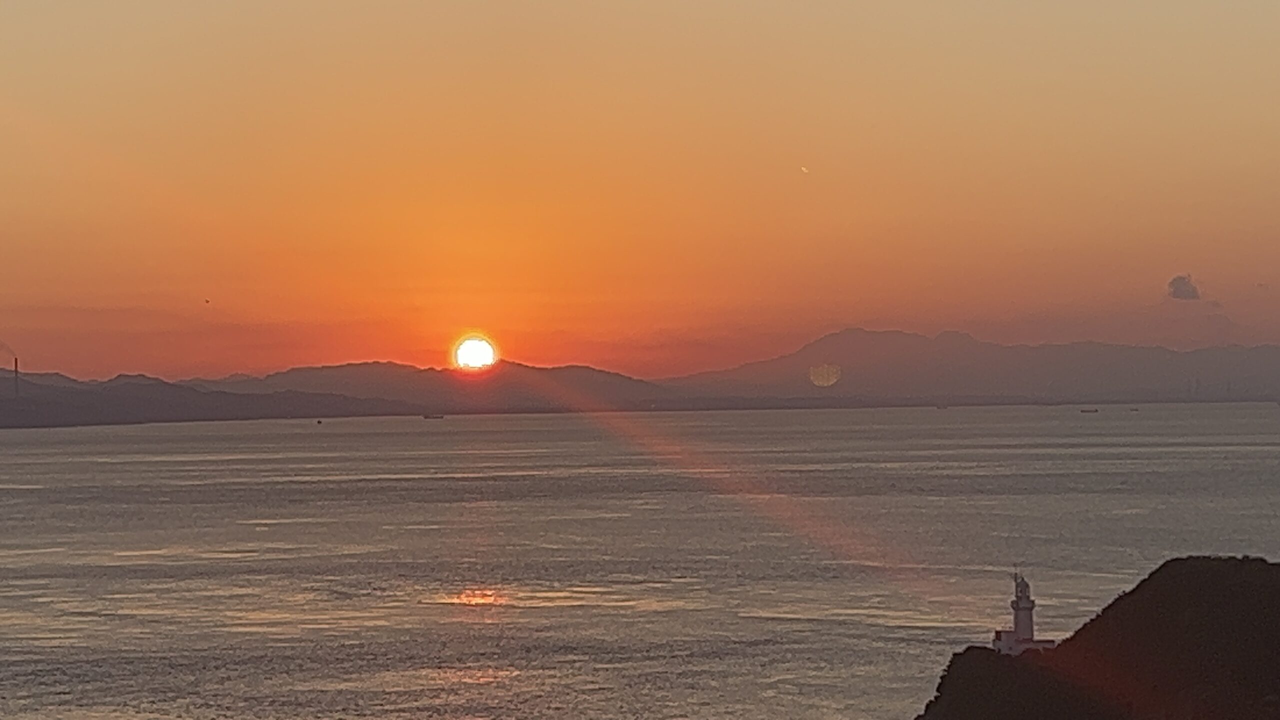 冬の宇和海の夕日——燃えるオレンジの空、山並みのシルエット、岬の灯台