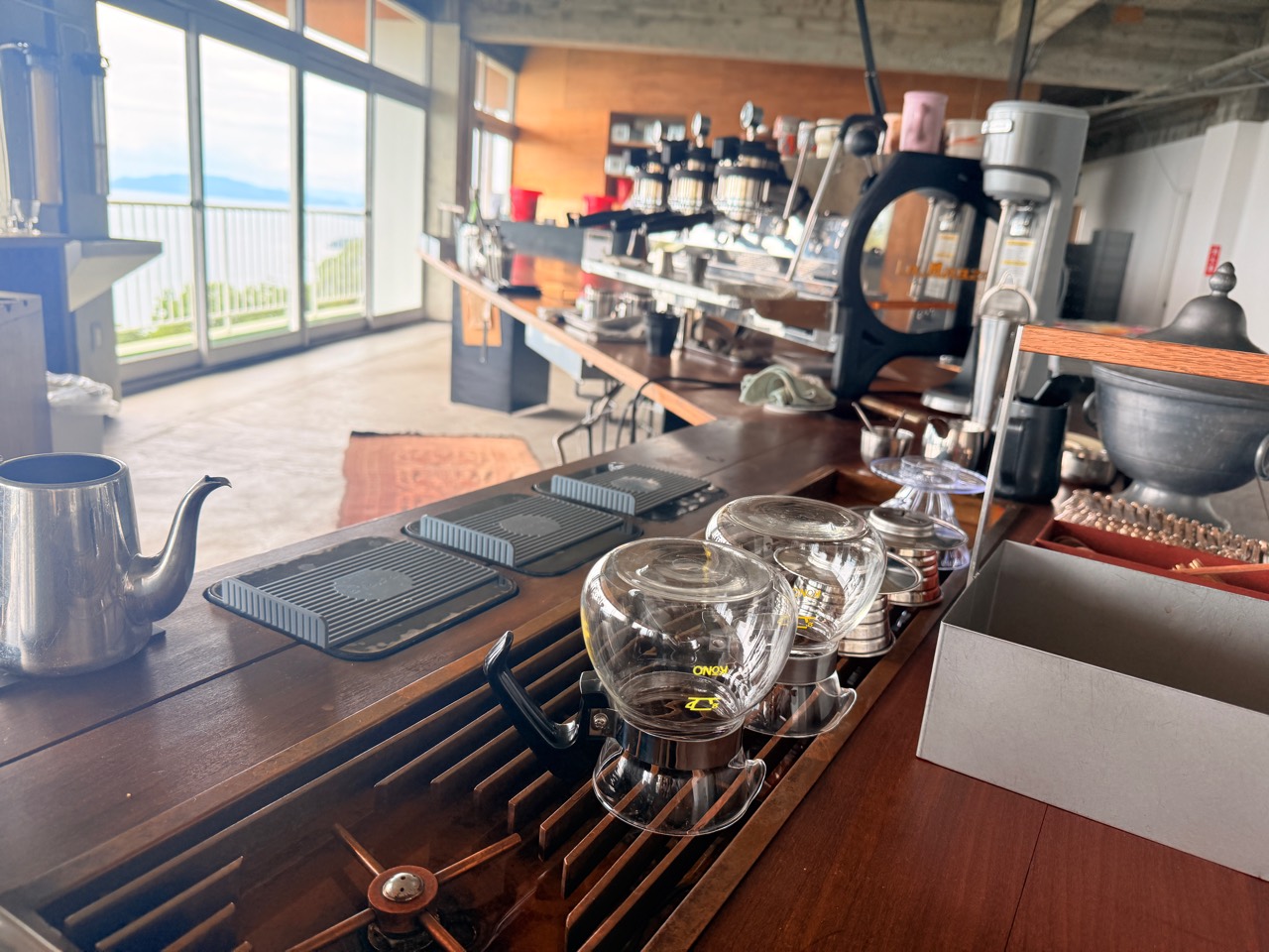 山の上のロースタリのカウンターに並ぶサイフォンとコーヒー器具
